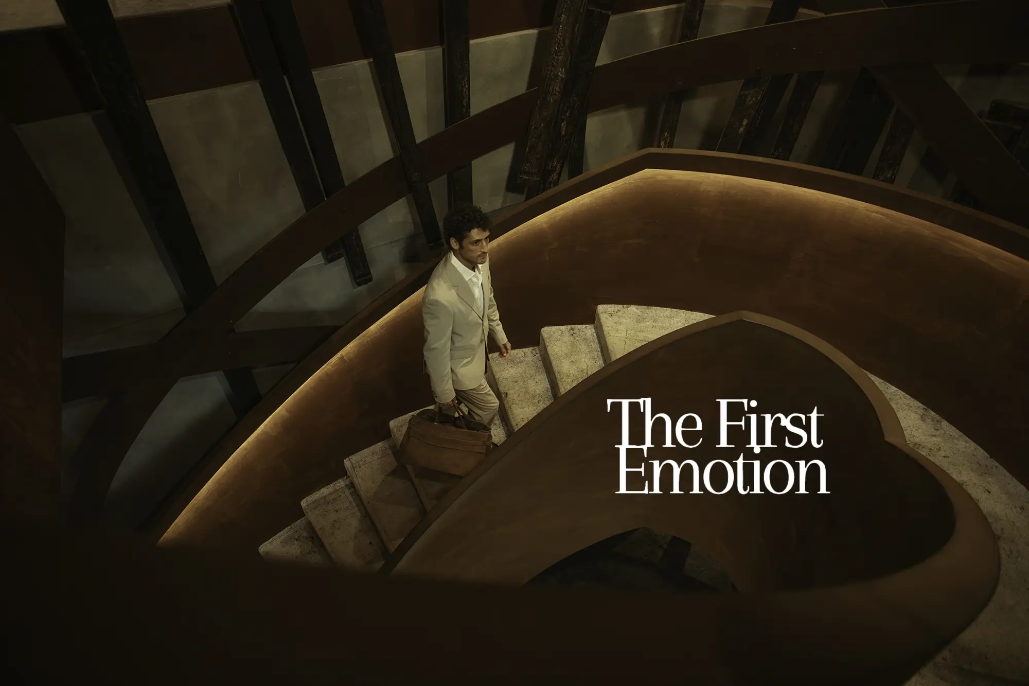 A guest in a cream suit climbing the curved wooden staircase of Forte de Gaia, suitcase in hand