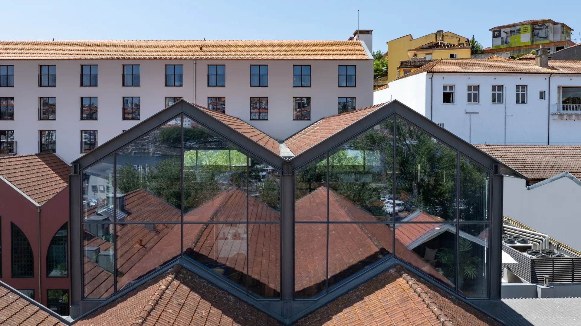 Forte de Gaia Hotel Porto: twin glass gables over terracotta rooftops in front of the historic white building