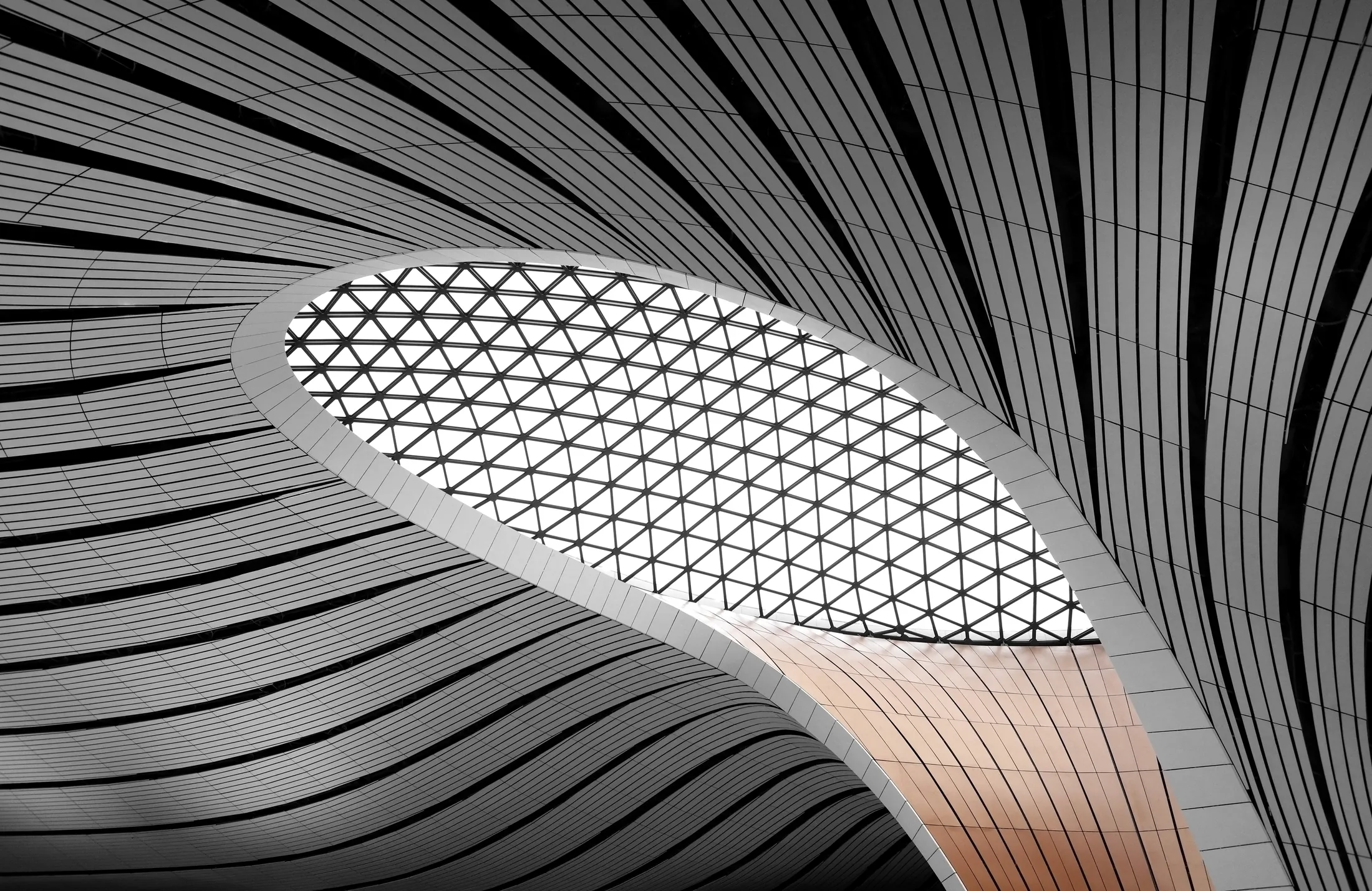 Curving facade of stone ribbons framing a latticed glass skylight