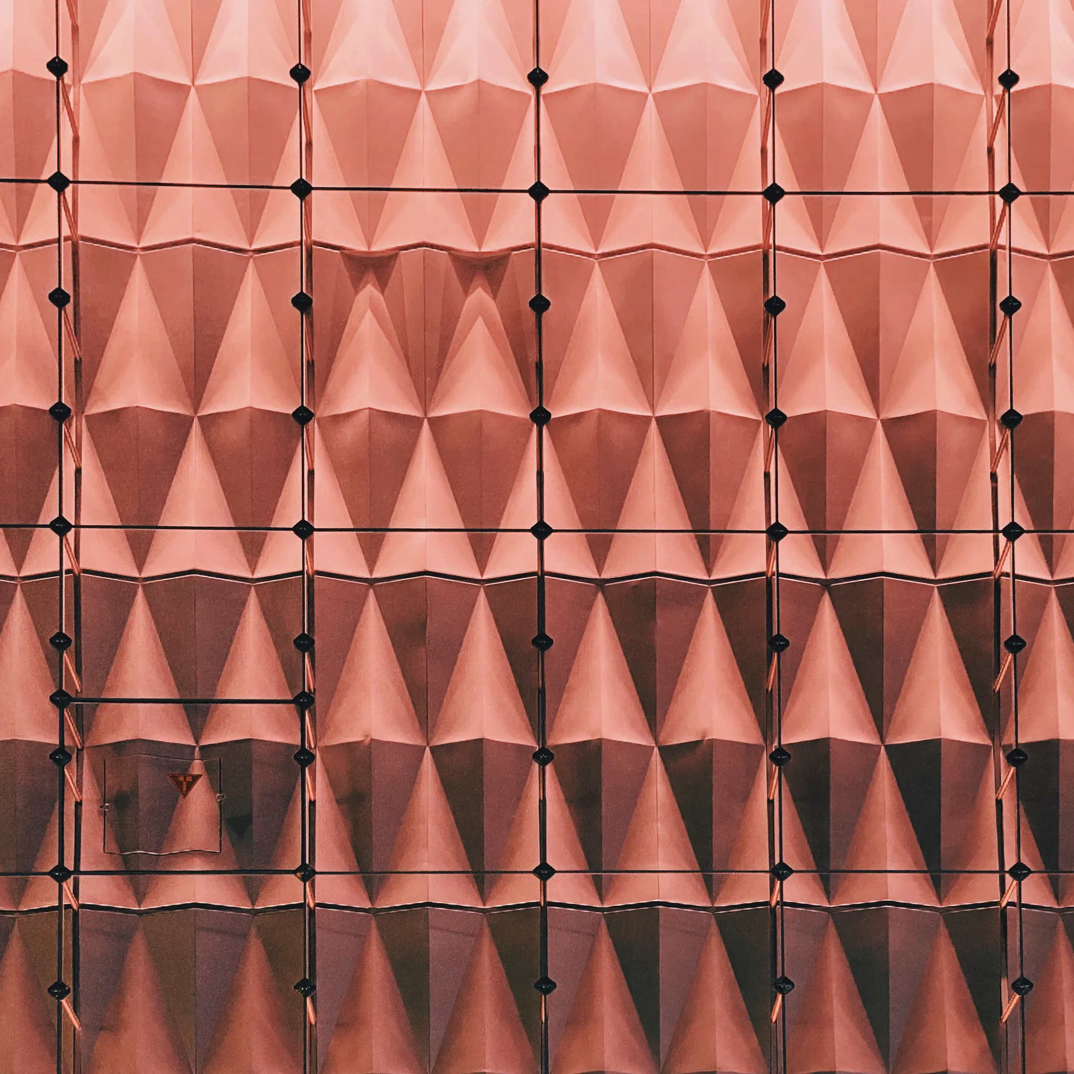Abstract facade of pink pyramidal panels in soft light