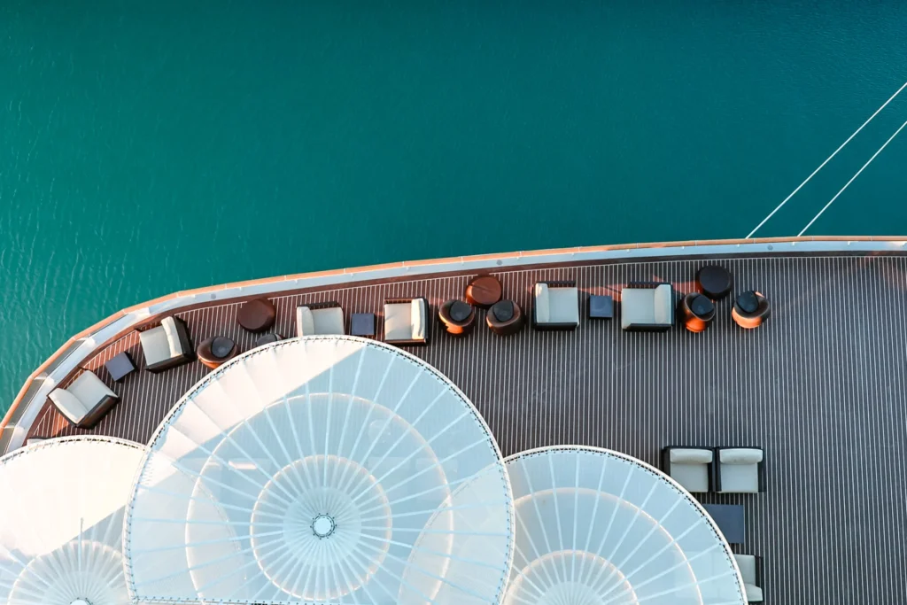 Aerial view of a cruise deck with loungers and white canopies over a calm blue sea