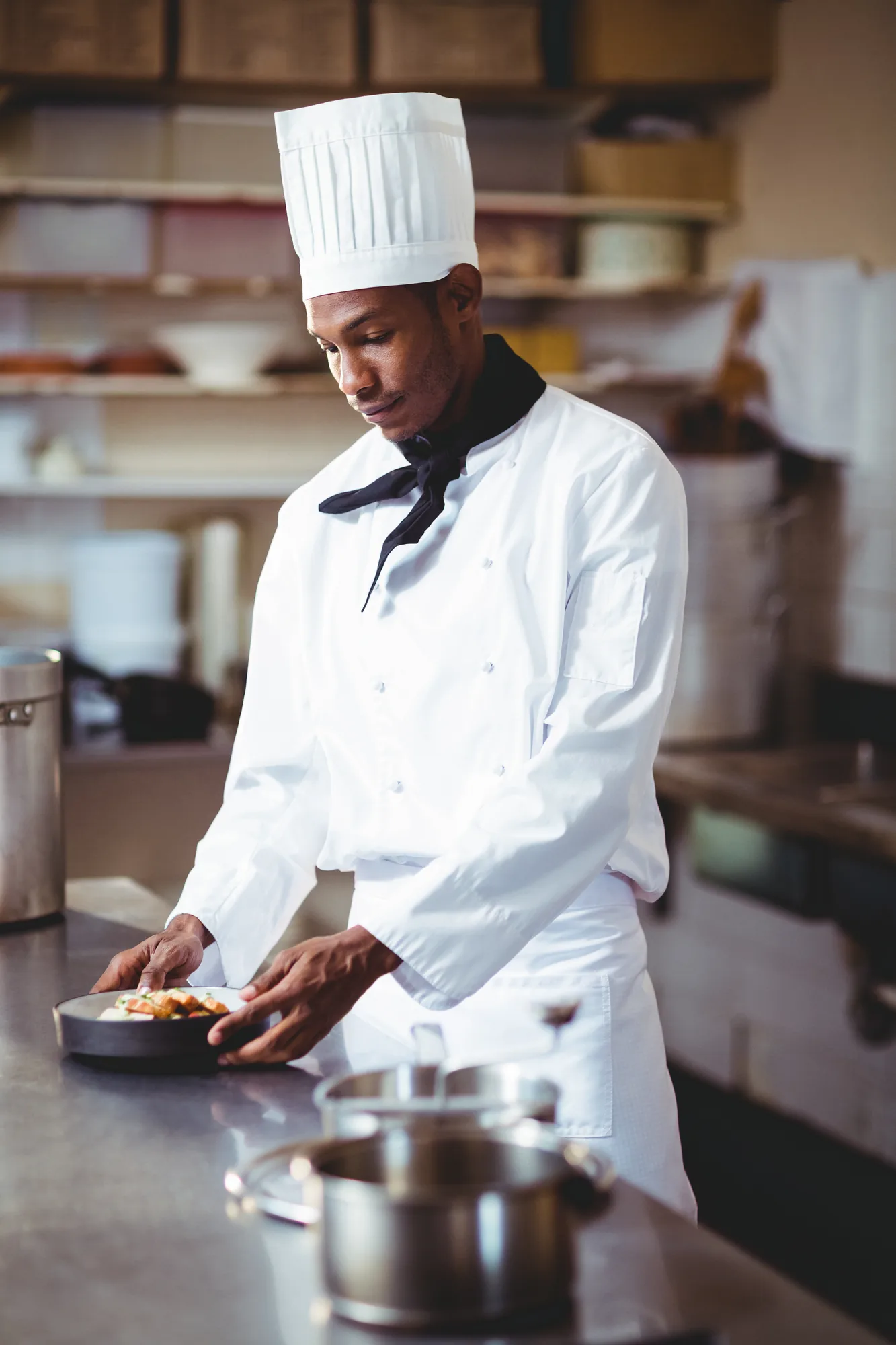 Chef in whites plating a dish in a restaurant kitchen