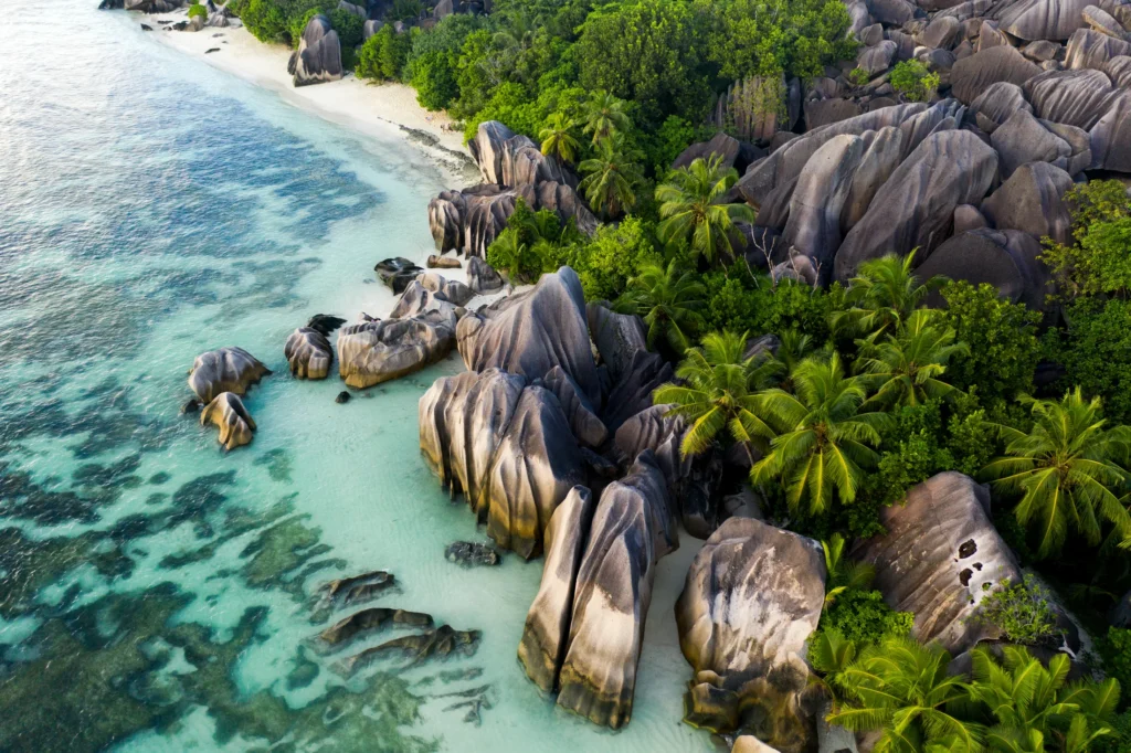 Granite boulders, palm trees and turquoise water at La Digue, Seychelles