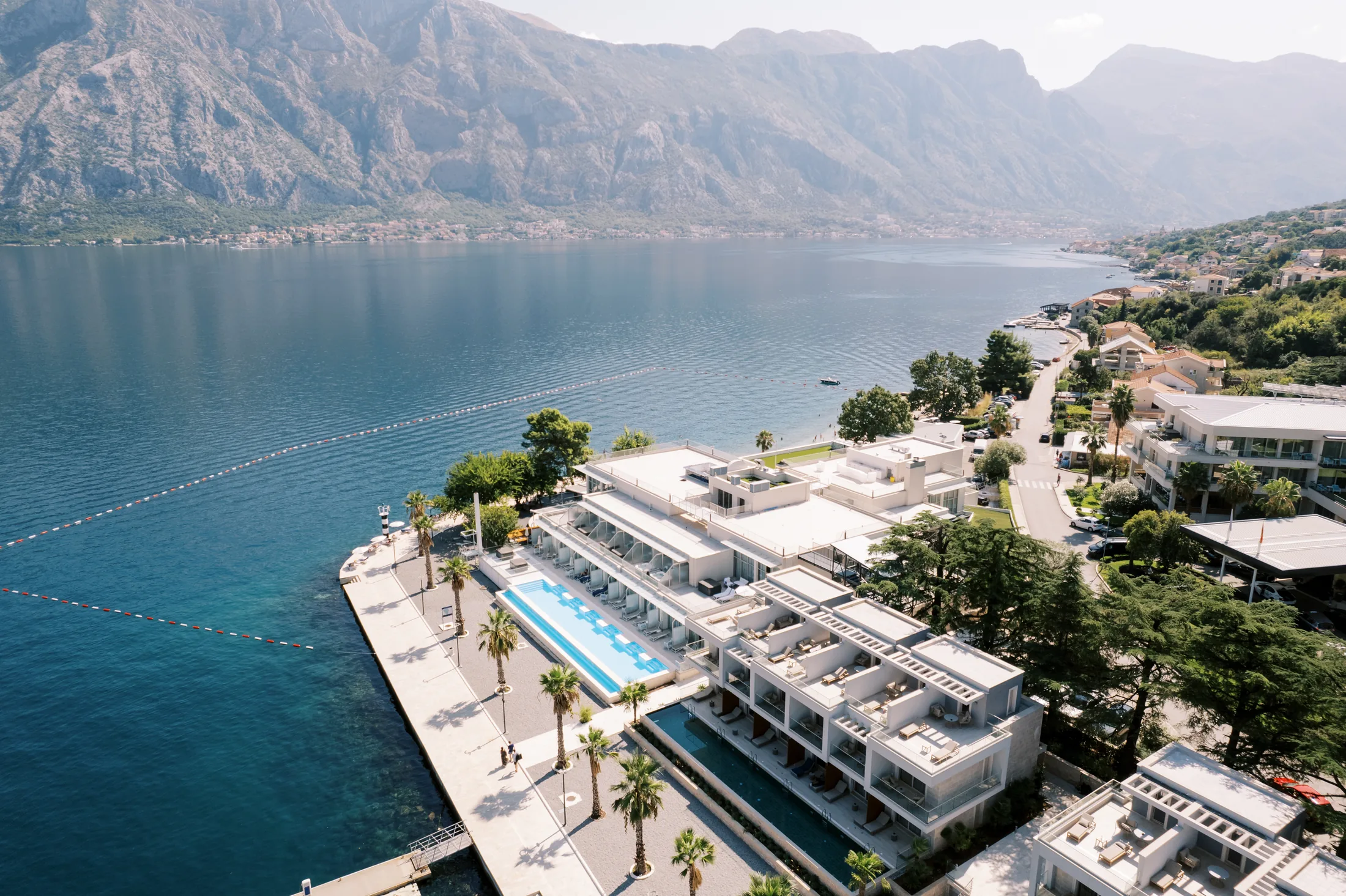 PSC-News-Next-Traveller-01 · Permanent State of Creation Resort on the shore of the Bay of Kotor, with pools, terraces and mountains behind