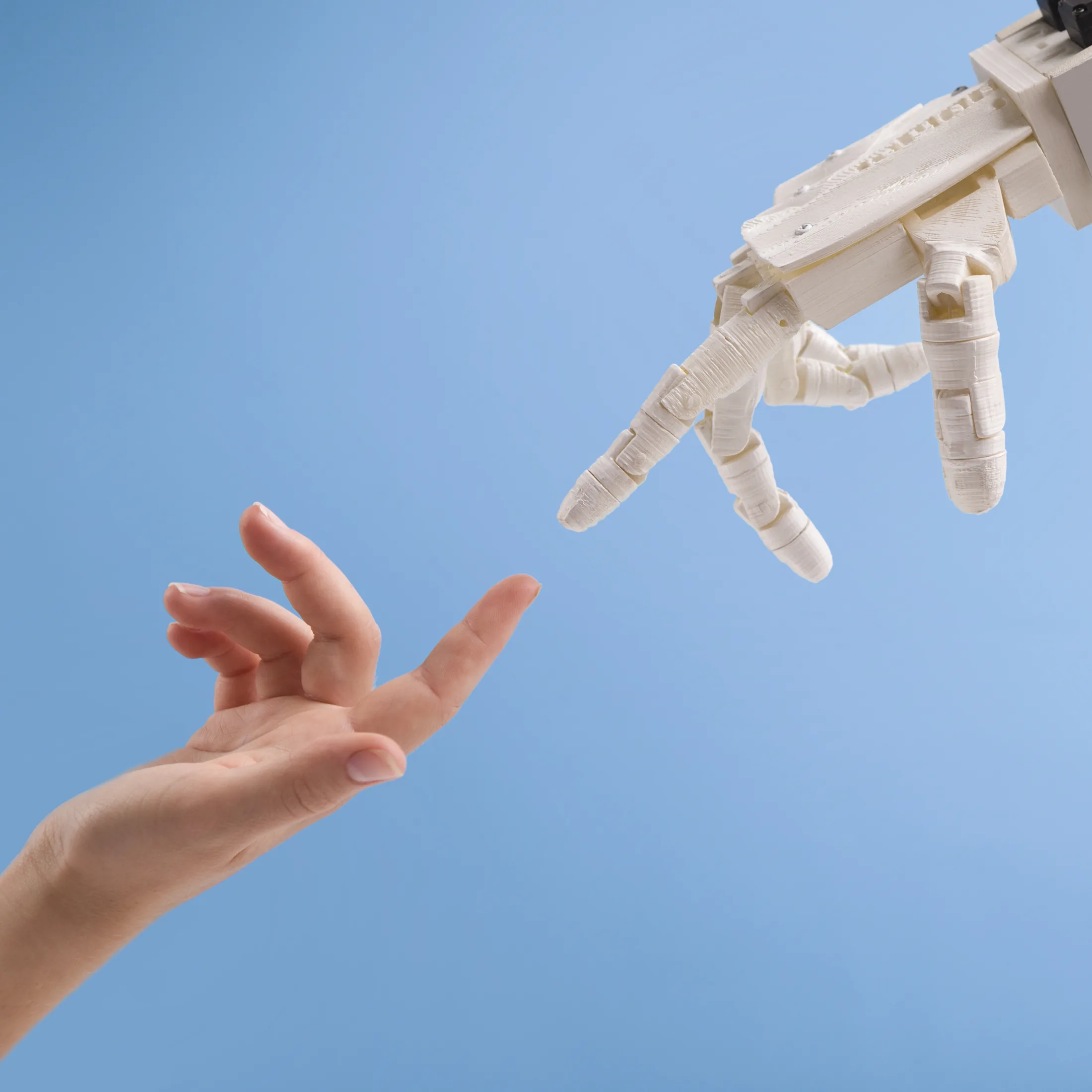 PSC-News-Next-Traveller-02 · Permanent State of Creation A human hand reaching towards a robotic hand against a blue sky