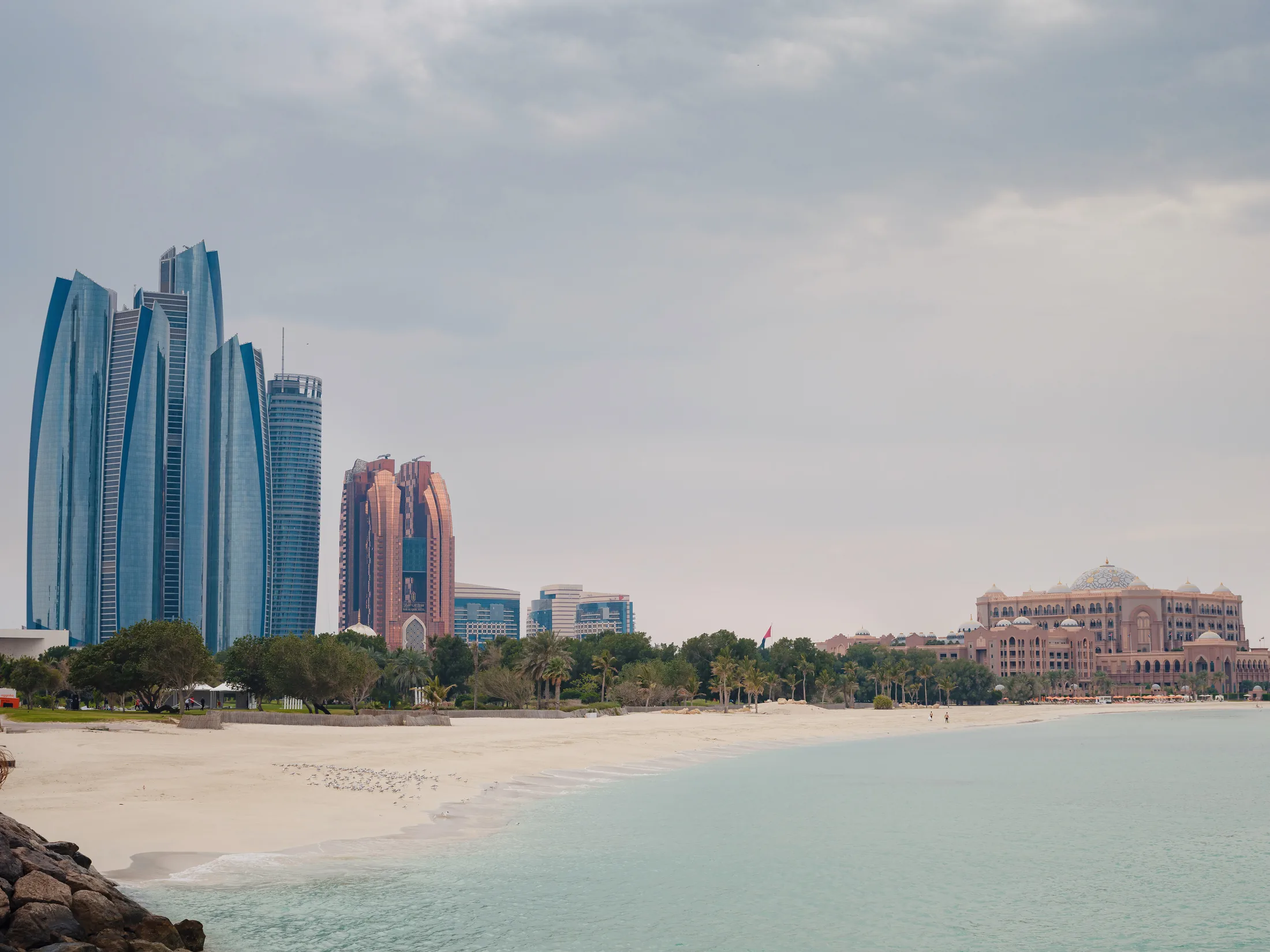 PSC-News-Next-Traveller-04 · Permanent State of Creation Abu Dhabi skyline and beach seen across calm turquoise water