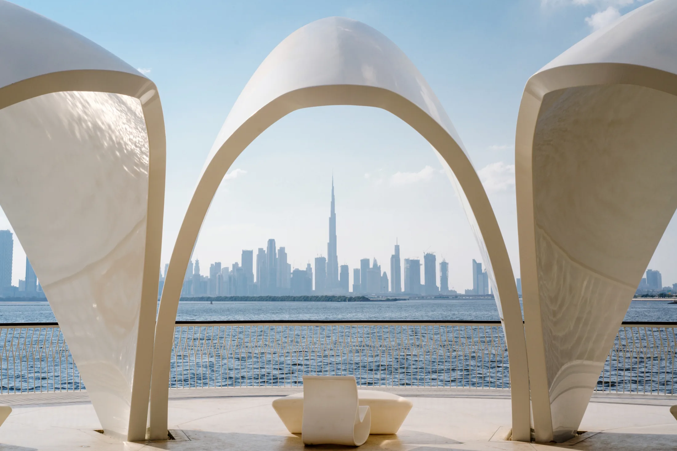 PSC-News-Next-Traveller-07 · Permanent State of Creation Dubai skyline framed by a sculptural white arch on the waterfront