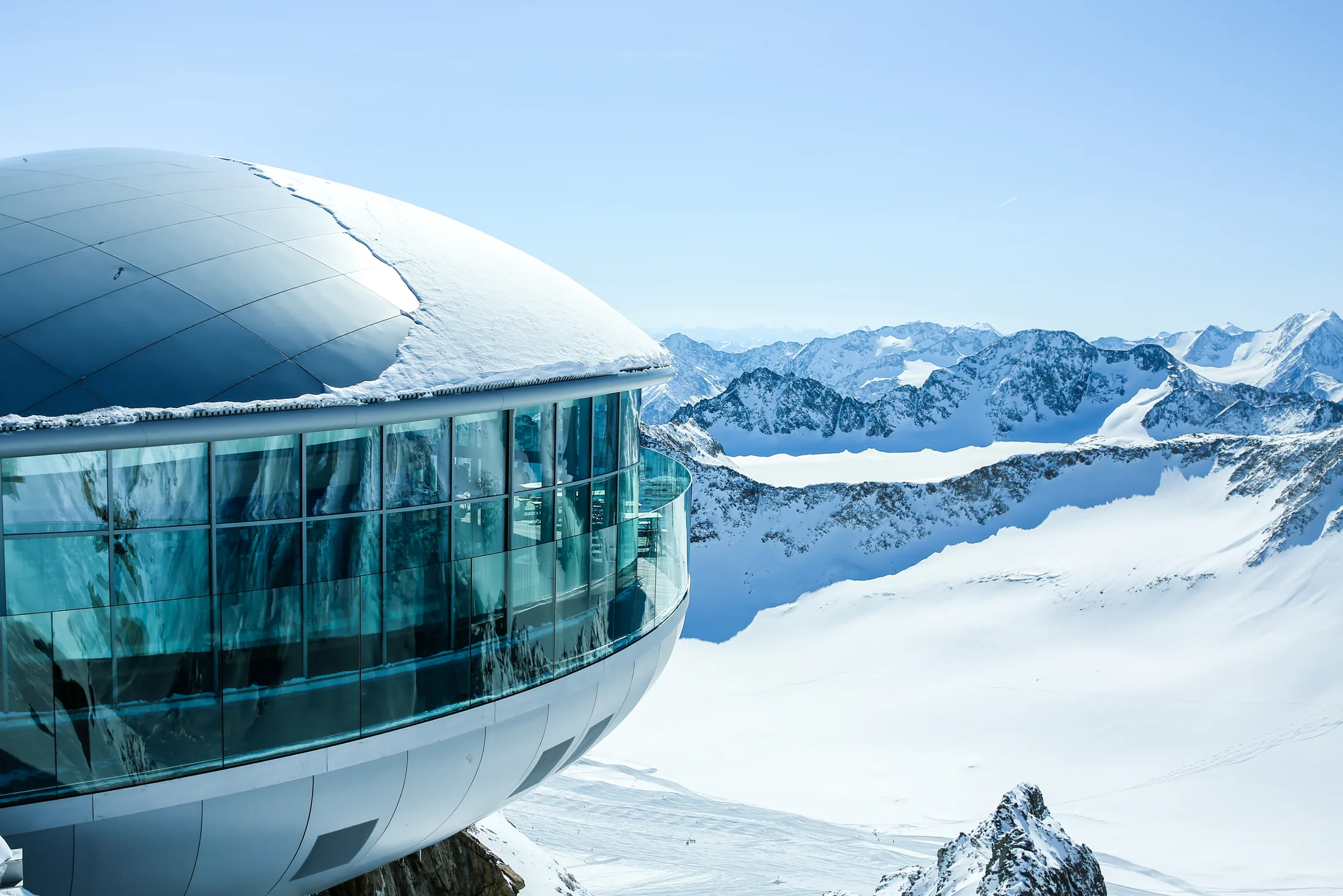 PSC-News-Next-Traveller-09 · Permanent State of Creation Glass structure perched high above a snowy mountain range