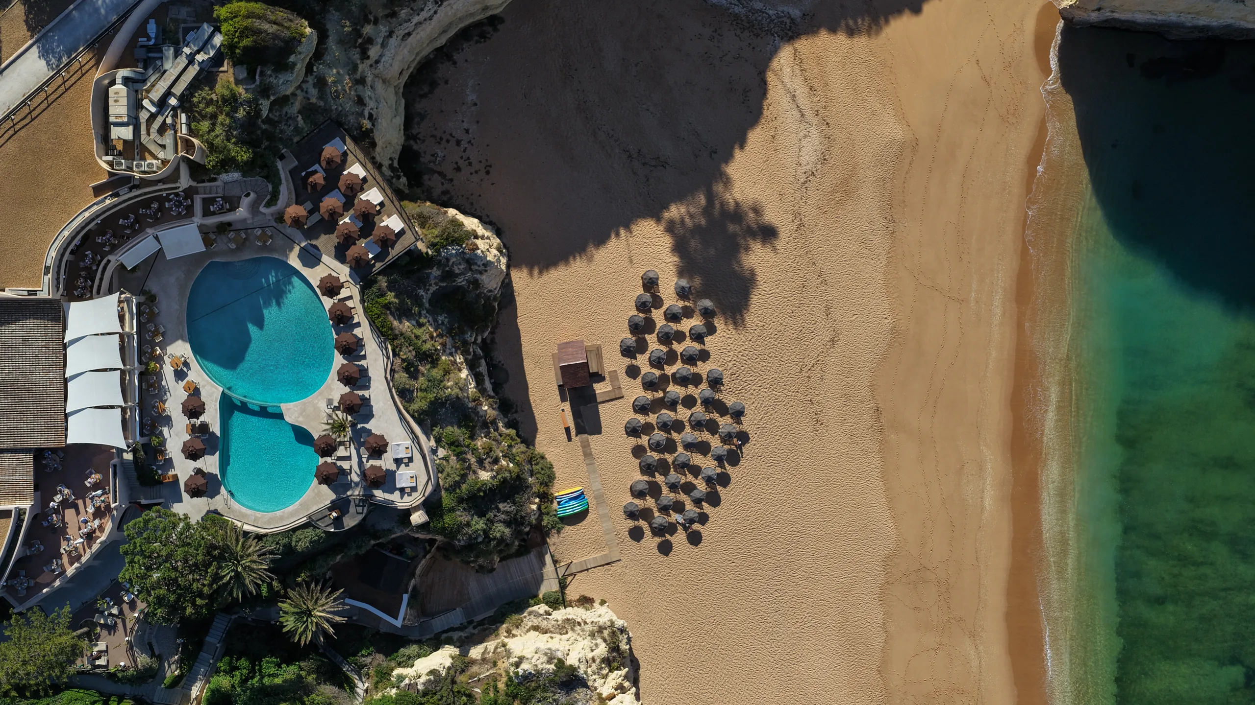 Aerial view of Vilalara Grand Hotel Algarve: pools, terraces and the sandy beach below the cliffs