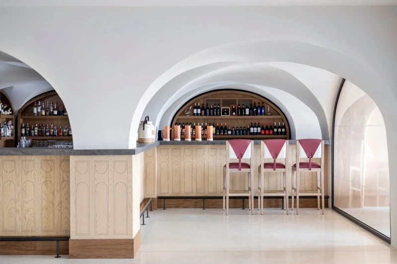Bar with wine arch and pink stools at A Costa Restaurant