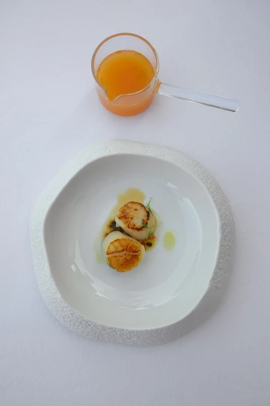 Scallops on white plate, orange sauce jar at Coral, Edén do Mar